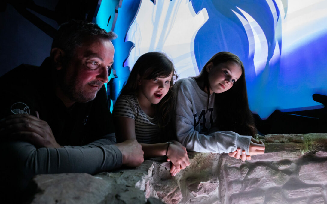 A family enjoying the mystery of Loch Ness in the myths and legends room at the Loch Ness Centre
